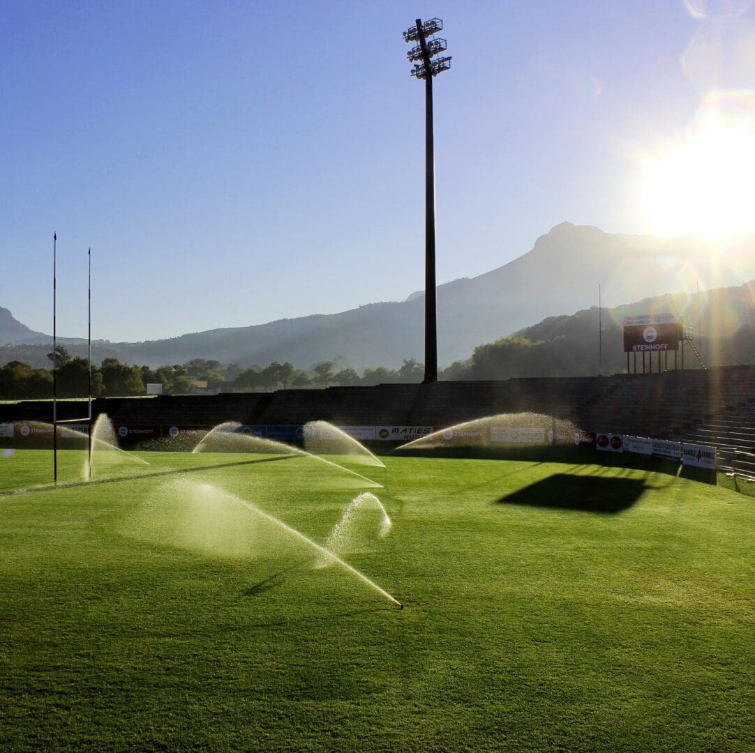 A field with sprinklers spraying water on it.